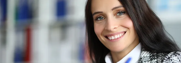 A smiling female with dark hard standing at the end of a desk