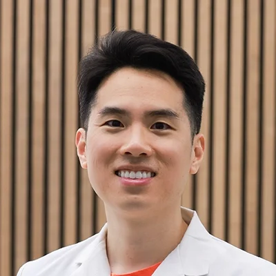Orthodontist The Woodlands TX Jeff Shao Jeff Shao Smiling In Front Of Wooden Wall